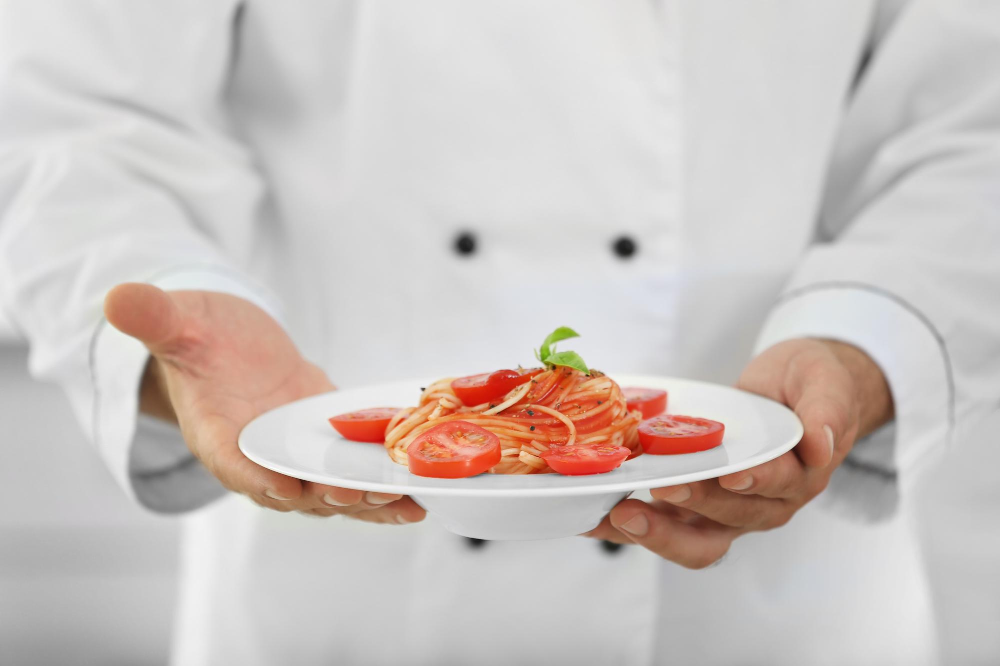Chef arranging plated dish in bright kitchen